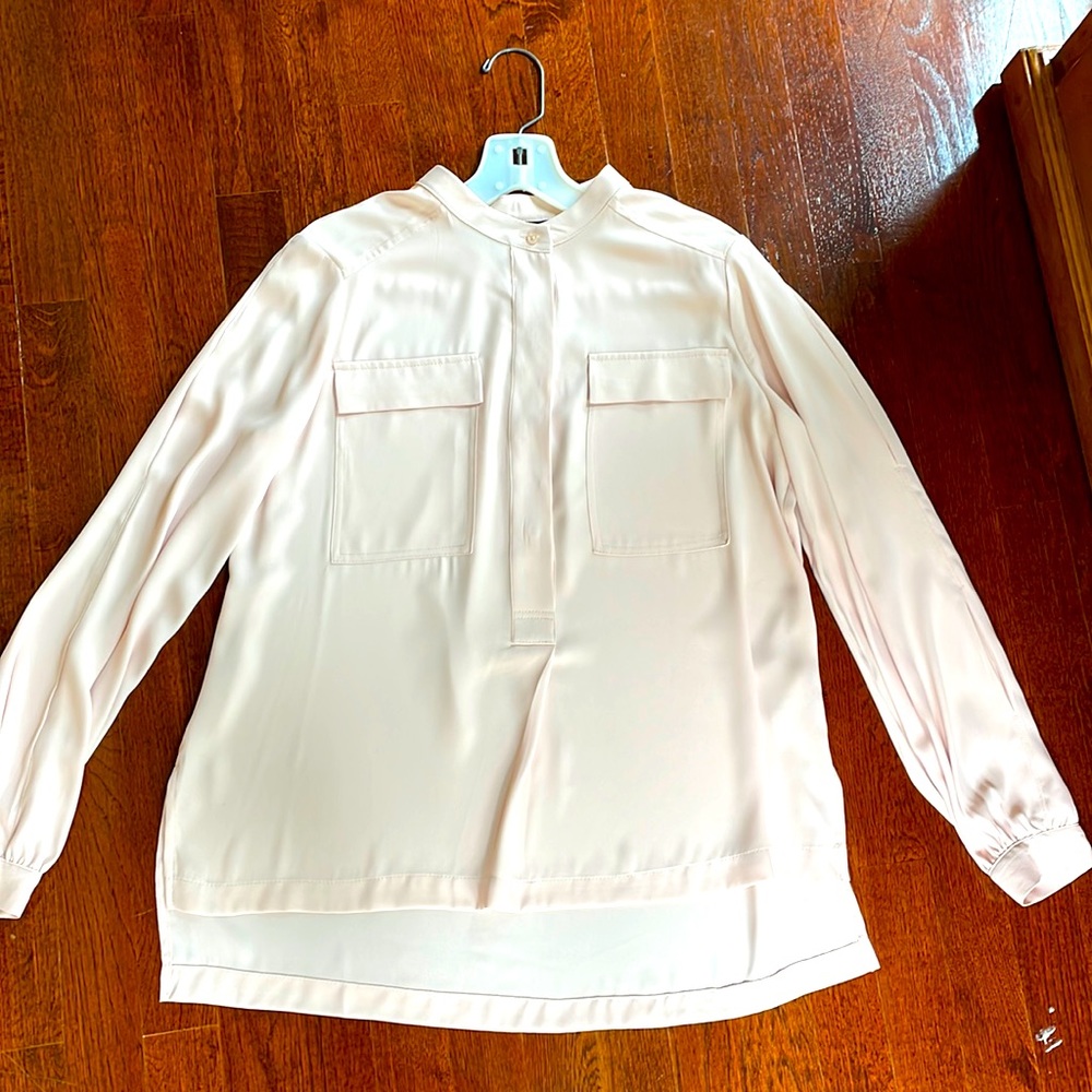 Light blush pink long sleeve draped blouse with pockets on front.
